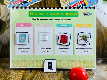 Educational card with cutout icons for Prophets and Holy Books on a wooden surface.